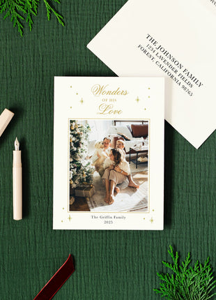 Holiday-themed card with gold foil and envelope on a green surface with decorative elements
