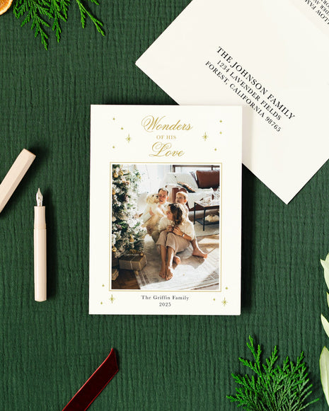 Holiday-themed card with gold foil and envelope on a green surface with decorative elements